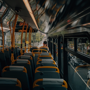 Interior de un autobús urbano con asientos vacíos y pasajeros al fondo